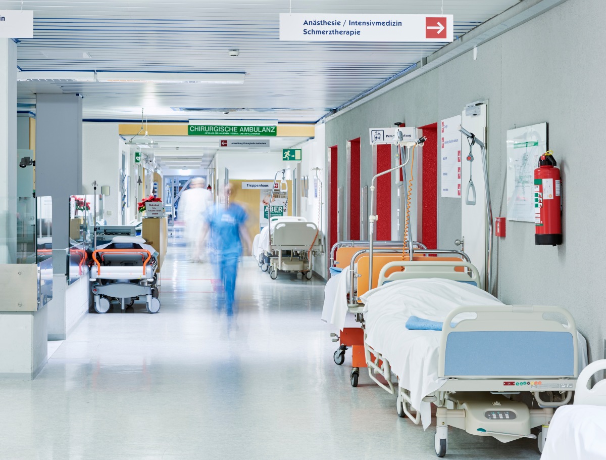 Flur im Krankenhaus mit unscharfem Arzt in Bewegung und Lift rot und Bett